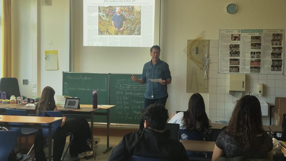 Journalist Marc Prams (Saarbrücker Zeitung) im Klassenzimmer vor einer Schulklasse 